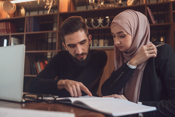 A business team of young man and Muslim woman working together on the project planning strategy in the modern office or Arabic college students study together in the library on the university campus.