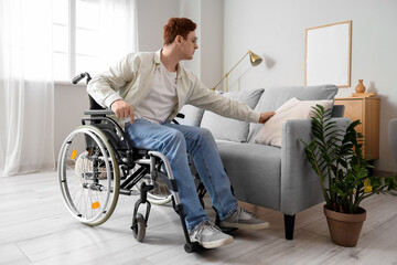 Young man in wheelchair with cushion on sofa at home
