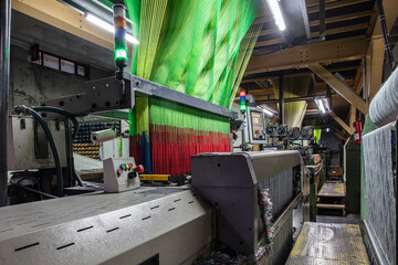 Synthetic yarns for carpet factory, carpet production, weaving looms. Interior of a Carpet Weaving Factory. Spool Sewing Thread Rack at Textile Weaving Mill.