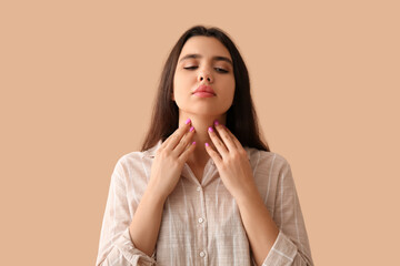 Young woman with thyroid gland problem on beige background