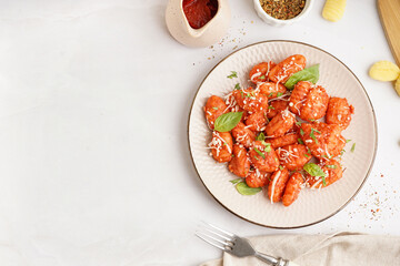 Plate of tasty gnocchi with cheese on white background