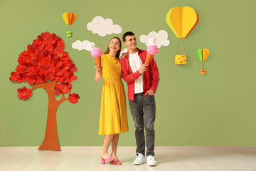 Young couple with ice cream figures near decorated green wall. Valentine's Day celebration