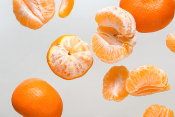 Flying sweet ripe mandarins on grey background