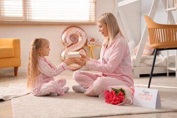 Little girl and her mother with gift in bedroom. International Women's Day celebration