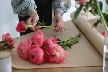 Florist making beautiful peony bouquet at table, closeup