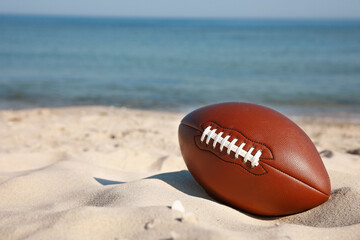 American football ball on beach. Space for text