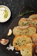 Tasty baguette with garlic served on grey textured table, flat lay