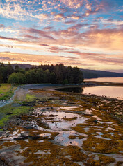 View of Rocky shore on Pacific Ocean West Coast during Dramatic Sunset.