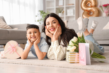 Cute little boy and his mother with gifts, tulips and greeting card at home. International Women's Day - obrazy, fototapety, plakaty