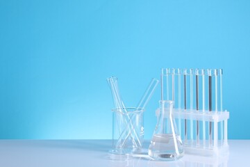 Laboratory analysis. Different glassware on table against light blue background, space for text