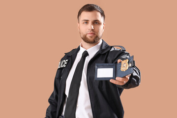 Male police officer with identification badge on beige background