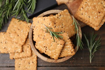 Cereal crackers with flax, sesame seeds and rosemary on wooden table, flat lay