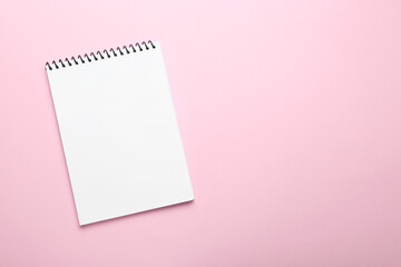 One notebook on pink background, top view. Space for text