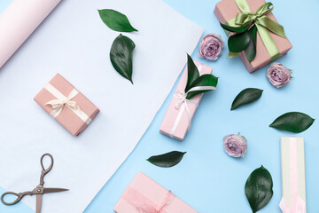Gift boxes, wrapping paper with beautiful roses and leaves on blue background. International Women's Day