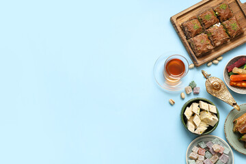 Composition with traditional Eastern sweets, tea and Aladdin lamp for Ramadan on color background
