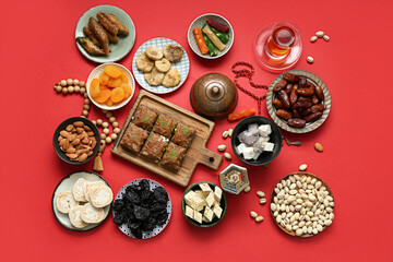 Composition with different Eastern sweets, Muslim lantern and tasbih for Ramadan on red background