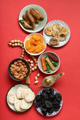 Composition with tasty Eastern sweets, tasbih and Aladdin lamp on red background