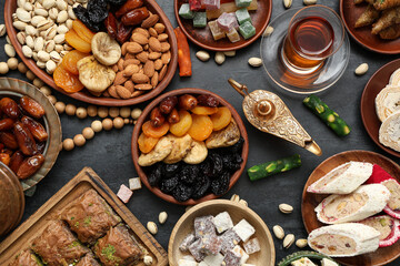 Composition with traditional Eastern sweets, Aladdin lamp and tasbih for Ramadan on dark background