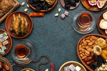 Fototapeta na wymiar Frame made of traditional Eastern sweets and tea for Ramadan on dark color background