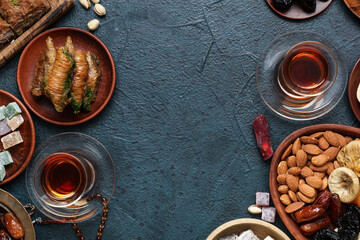 Composition with different Eastern sweets and tea for Ramadan on dark color background