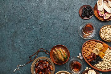 Composition with traditional Eastern sweets, tea and tasbih for Ramadan on dark color background