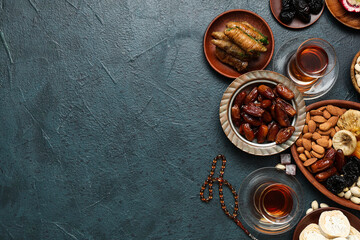 Fototapeta na wymiar Composition with traditional Eastern sweets, tea and tasbih for Ramadan on dark color background