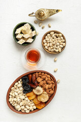 Composition with traditional Eastern sweets, tea and Aladdin lamp for Ramadan on light background