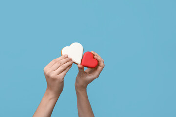 Woman with heart-shaped cookies on blue background. Valentine's Day celebration