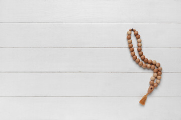 Prayer beads for Ramadan on white wooden background