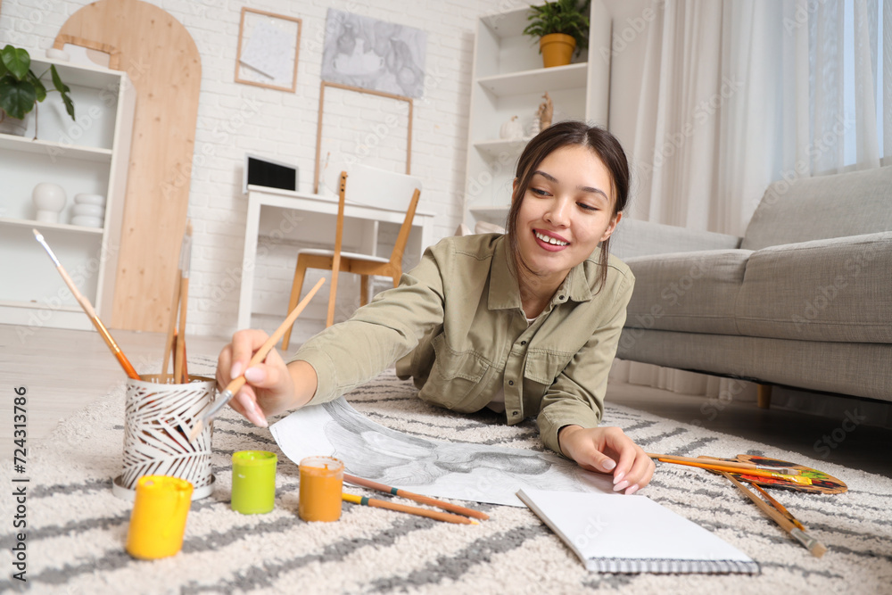 Wall mural Female Asian artist drawing on floor in workshop