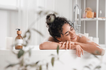 Obraz na płótnie Canvas Young African-American woman taking bath at home