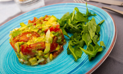 Image of delicious salad guacamole with fresh tomatoes and arugula at plate