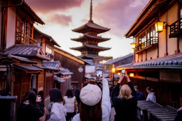 Rolgordijnen Yasaka Pagoda view and Hokan-ji Temple from Yasaka Dori street in Kyoto, Japan. Popular touristic street leading to Kyomizu Dera,Young female tourist taking photo with a mobile phone during sunset. © maya1313