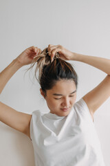 Fototapeta premium Asian woman in white t-shirt tying her hair to refresh and getting ready for the day.