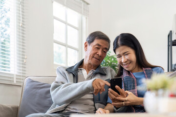 Portrait of Asian adorable senior couple using smartphone together video chatting with family in...
