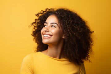 Portrait of happy african american woman with curly hair over yellow background