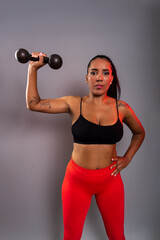 Beautiful brunette woman, in gym clothes, holding black dumbbells at head height. Healthy life.