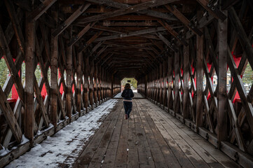 Young girl crossing a wood covered bridge over Gatineau river