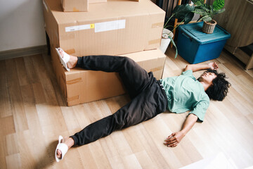Young Asian man working overload and sleep near cardboard boxes  at living room. Man tired after...