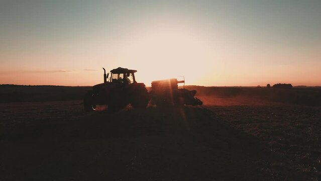 a tractor pulling a planter at sunset