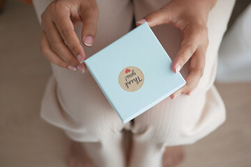  hand putting a thank you sticker on a gift box 