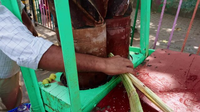 Traditional sugarcane juice extractor on a street cart with wood drums and crushed cane visible indian street food