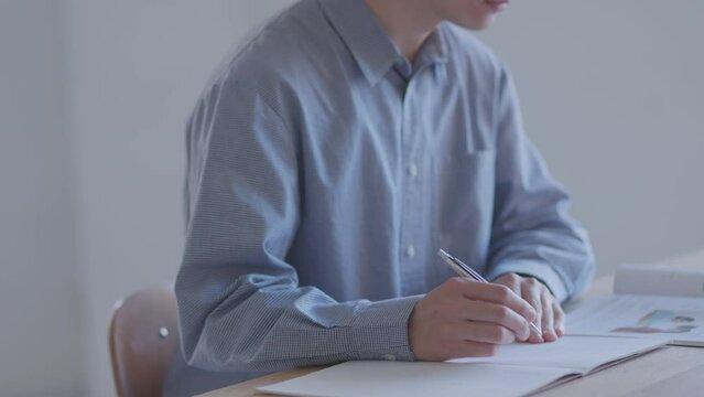 家のリビングで勉強をする日本人大学生の男性