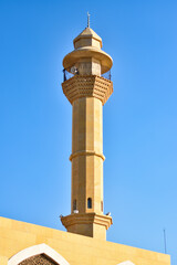 Fototapeta na wymiar Minaret of a yellow mosque with blue sky in the background in the city of Jeddah.