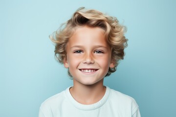 Portrait of a cute little boy with blond hair on a blue background