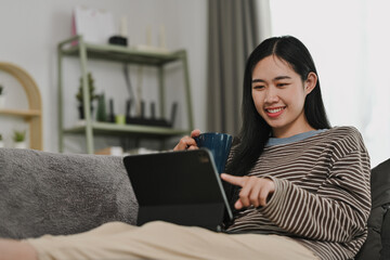 Beautiful young woman browsing internet or checking email on digital tablet