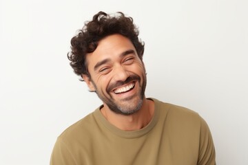 Portrait of a handsome young man with curly hair laughing against white background.