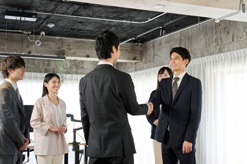 オフィスで握手をするアジア人ビジネスパーソン