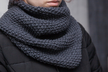 Hand made designed warm dark gray color knitted snood scarf on a girl's neck	