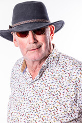 This portrait showcases a senior man exuding confidence and style. He's wearing a dark fedora hat paired with classic sunglasses, a look that commands attention. His direct gaze towards the camera